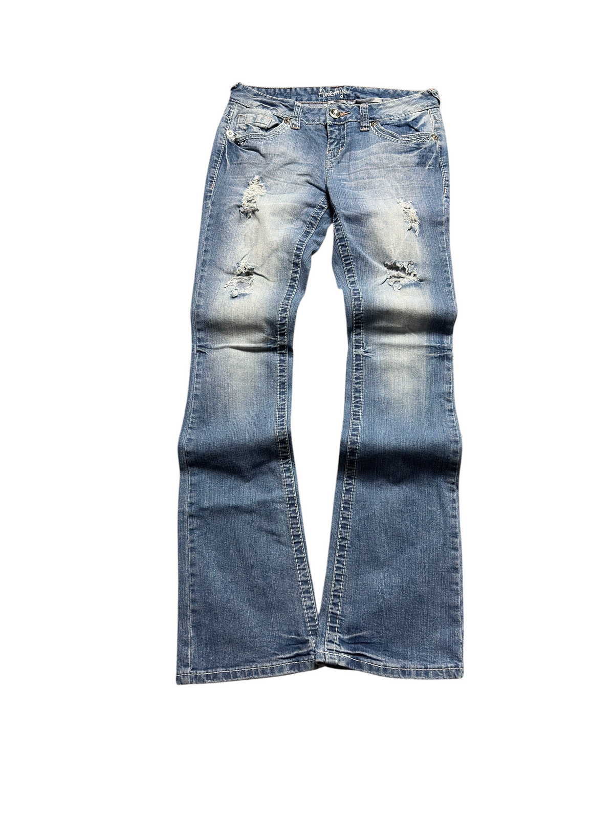 NinetyThree Amethyst medium-wash bootcut jeans with distressed front detailing and contrast stitching on a grey rug.